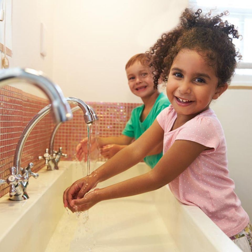 two elementary students washing hands at school
