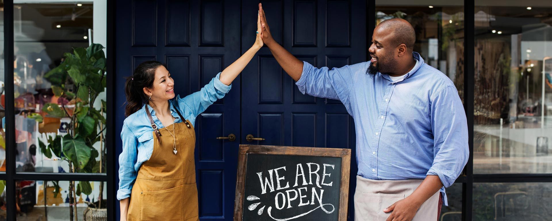 restaurant owners high five in front of business working towards waste reduction