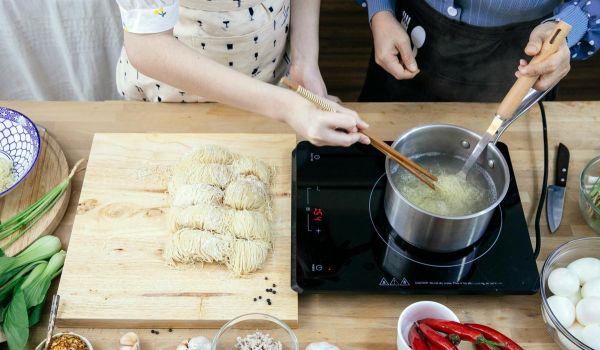 couple cooking fresh noodles using portable 1-burner induction cooktop