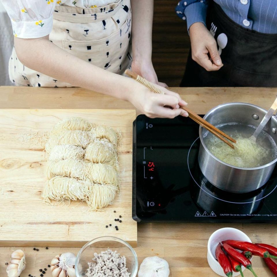 couple cooking fresh noodles using portable 1-burner induction cooktop