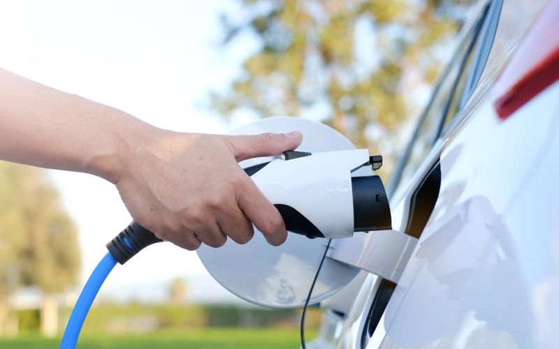closeup of person's hand plugging in electric vehicle to charge