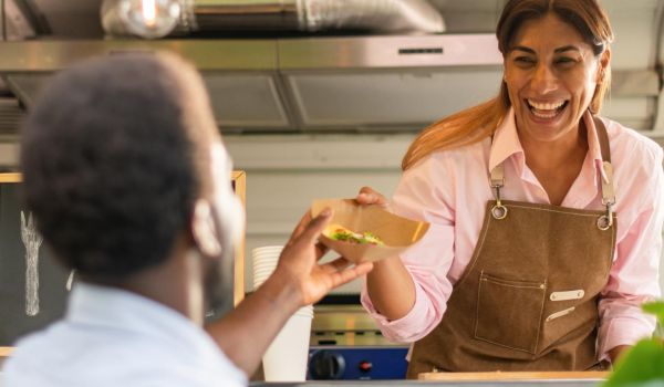food truck owner serves food in compostable containers with compostable utensils to customer