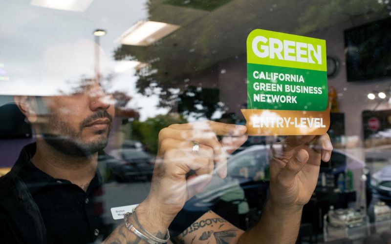 applying a California Green Business Network sticker to small business window