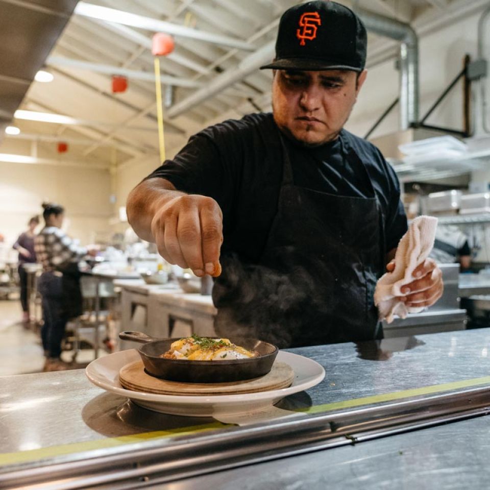 chef finishing dish with salt before service