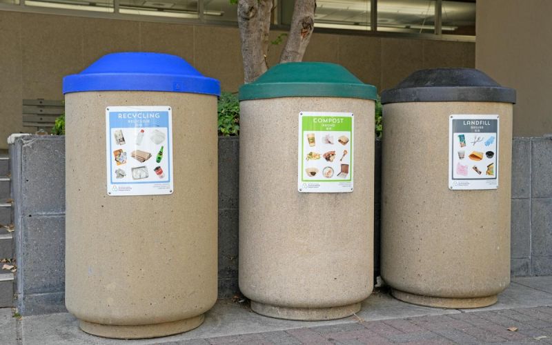 recycling, compost, and trash bins in front of a County facility