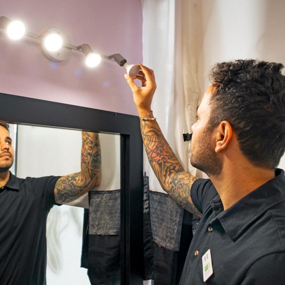 staff checking bathroom lightbulbs over mirror to ensure they are LED for green business certification