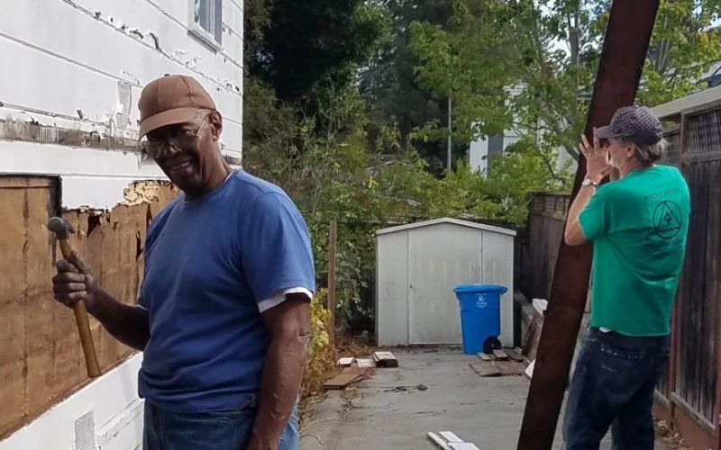 two San Mateo County residents deconstructing the side of a home
