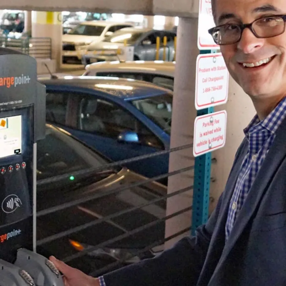 man using EV charging station in parking garage
