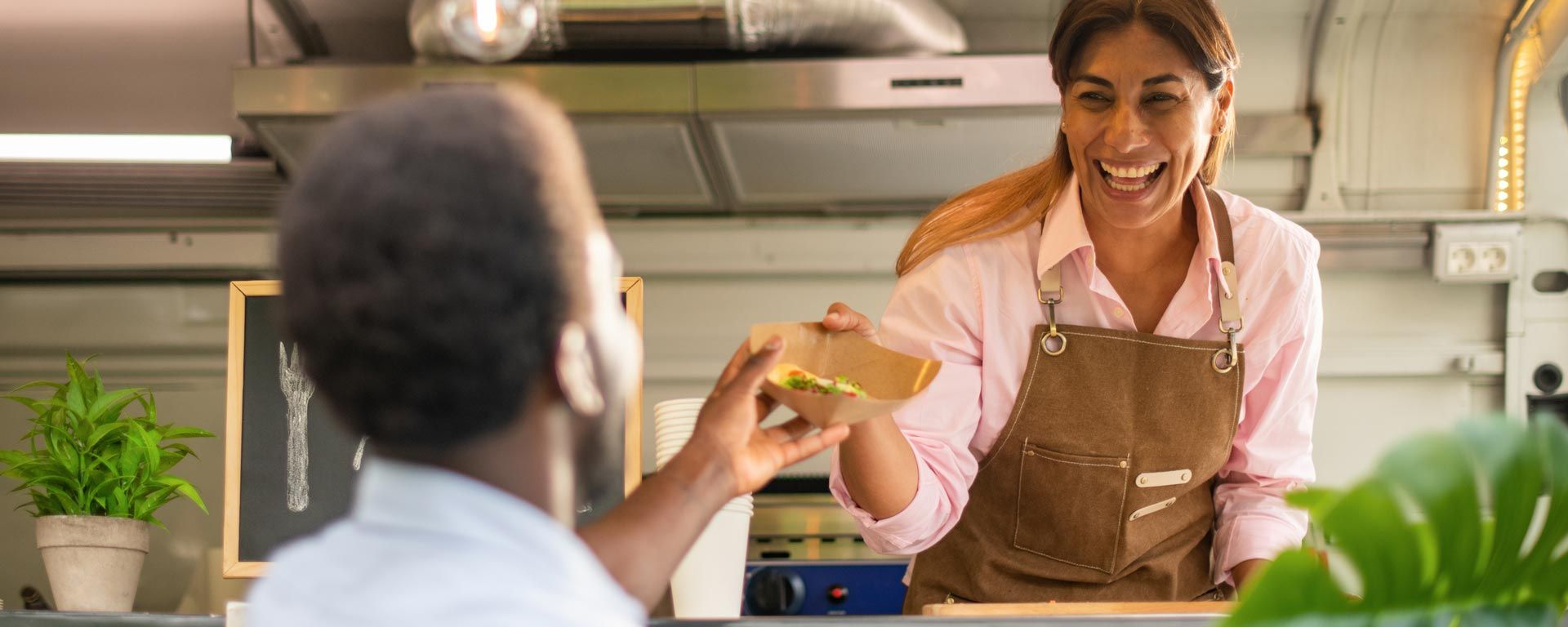 food truck owner serves food in compostable containers with compostable utensils to customer
