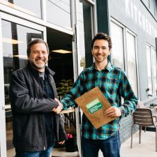 small business owner shakes hands with staff awarding green business certification  outside of his business