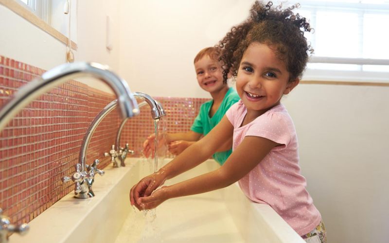 two elementary students washing hands at school