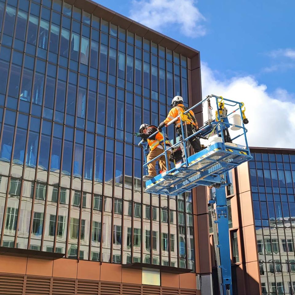 workers in lift outside building using green building practices