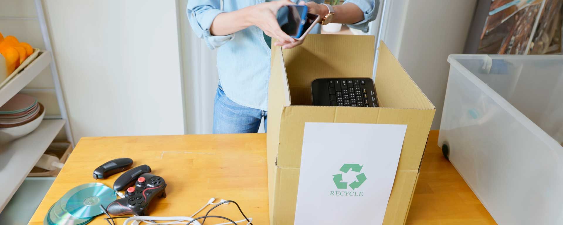 woman places old electronic devices into box for recycling