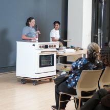 group of people watch an induction cooktop demonstration