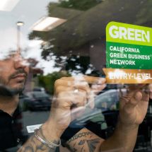 person applying a Green Business sign on window of a small business