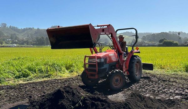 farmer spreading compost on field with tractor