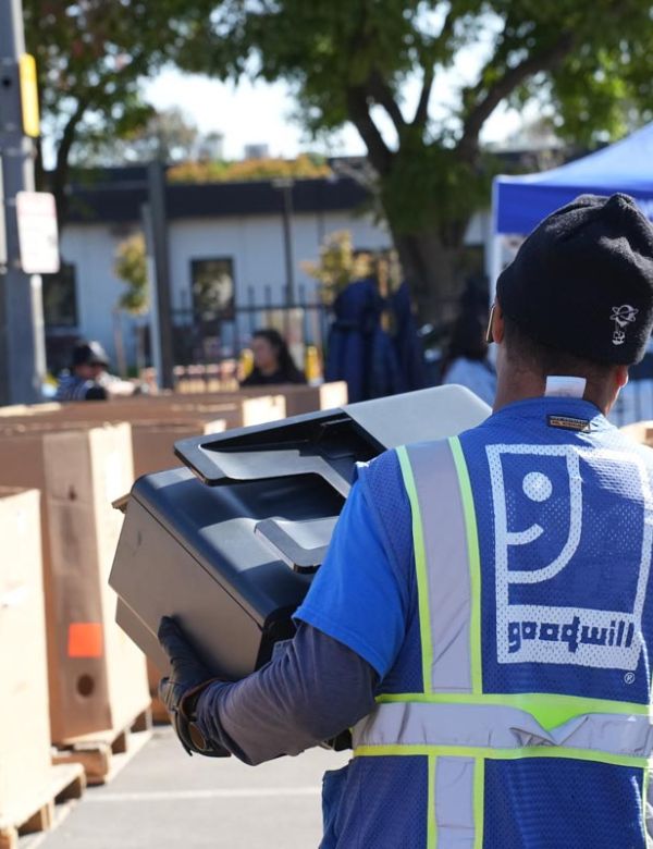 Goodwill employee carrying printer at electronics waste recycling event in San Mateo County