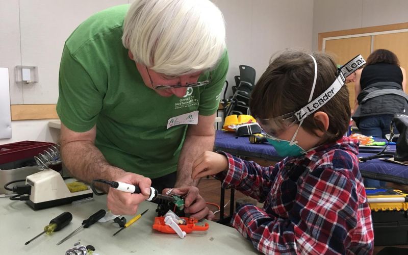 Fixit Clinic volunteer coach helps child repair electronic toy