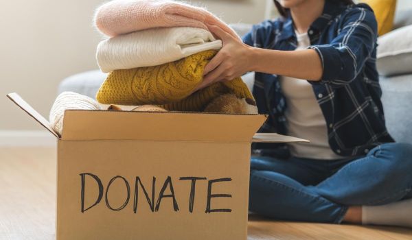 woman putting clothing into box for donating