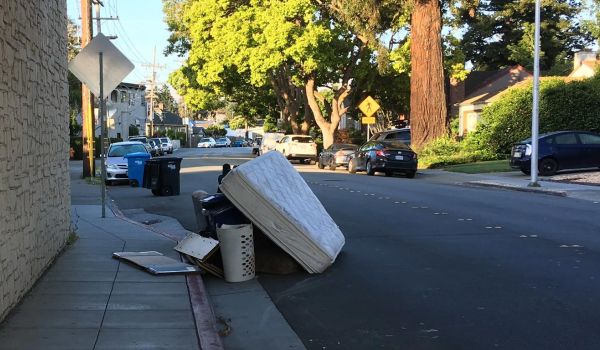 illegal dumping of trash and mattress on city roadside