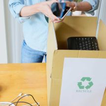 woman places old electronic devices into box for recycling