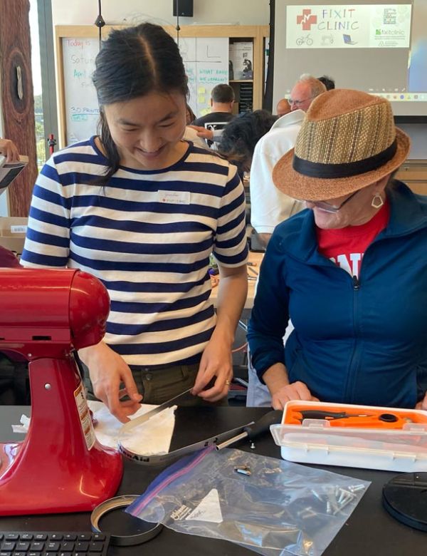 Two women work together to fix a standing mixer at San Mateo County Fixit Clinic