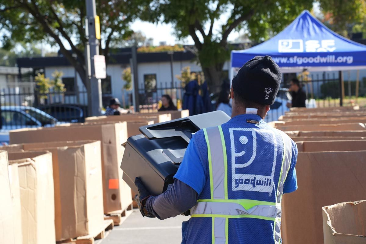 Goodwill employee carrying printer at electronics waste recycling event in San Mateo County