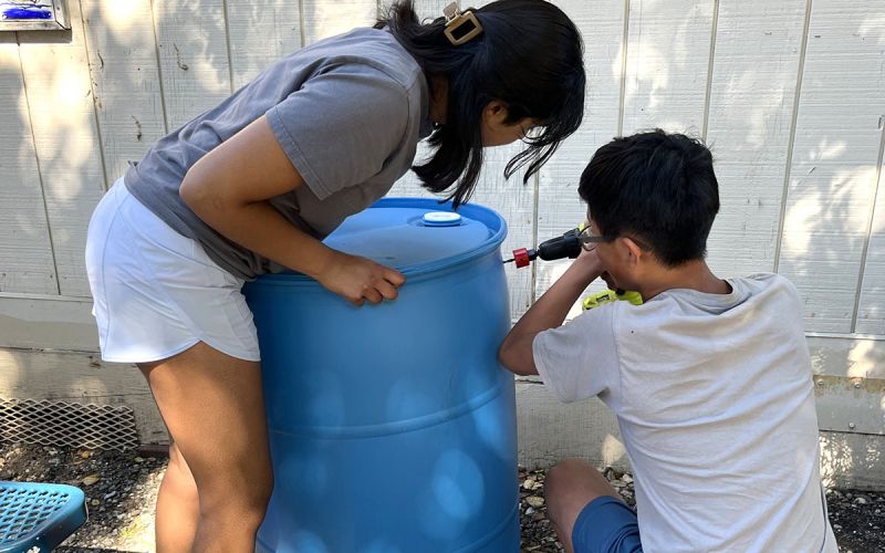 two-teens-installing-water-barrel