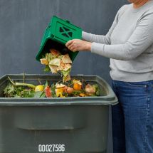 woman throwing food scraps into organics collection bin