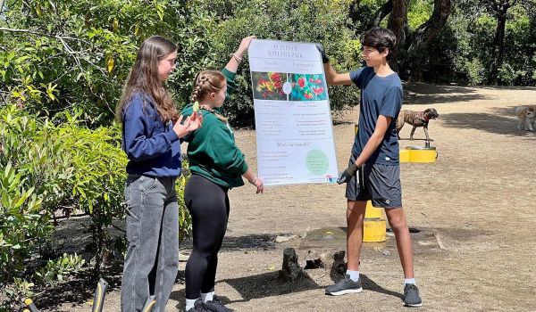three students in San Mateo County Youth Climate Action Program holding up sign in park
