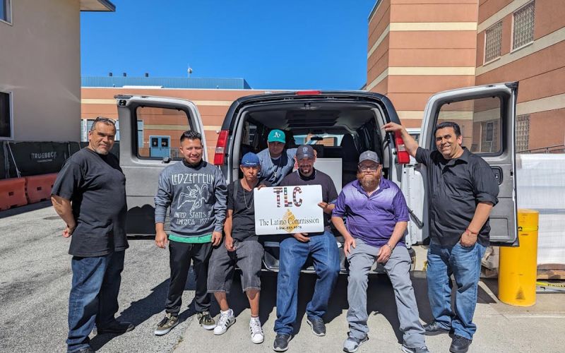 seven community partners standing in front of a van at a surplus event