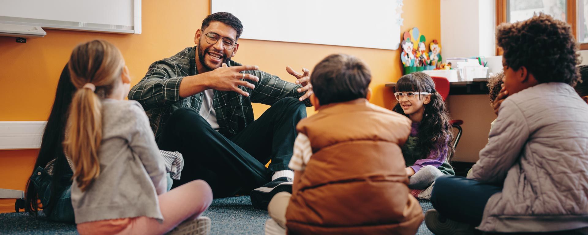 teacher sitting in a circle talking with a group of young students
