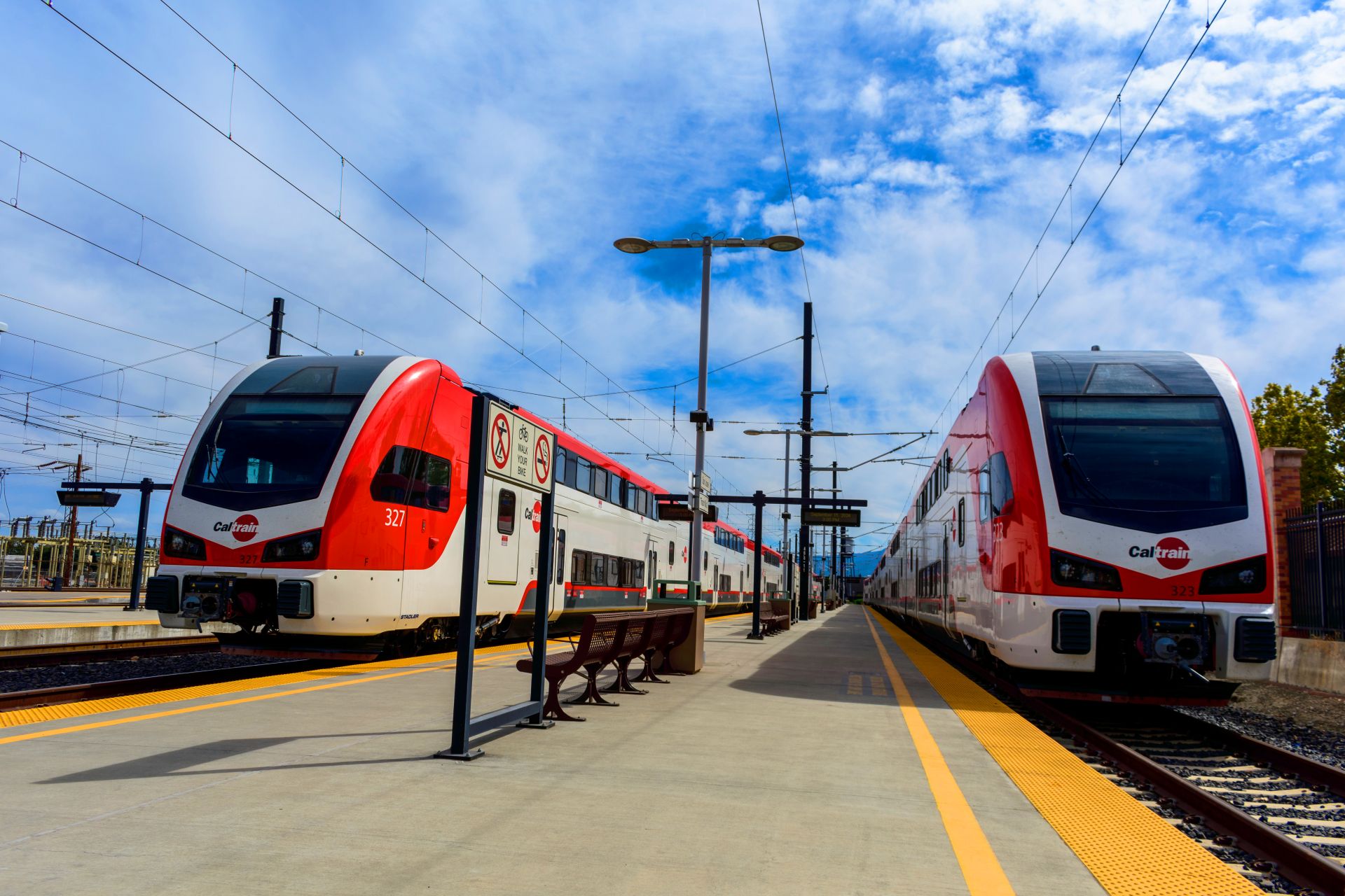 Caltrain station with two trains on either side of the platform.