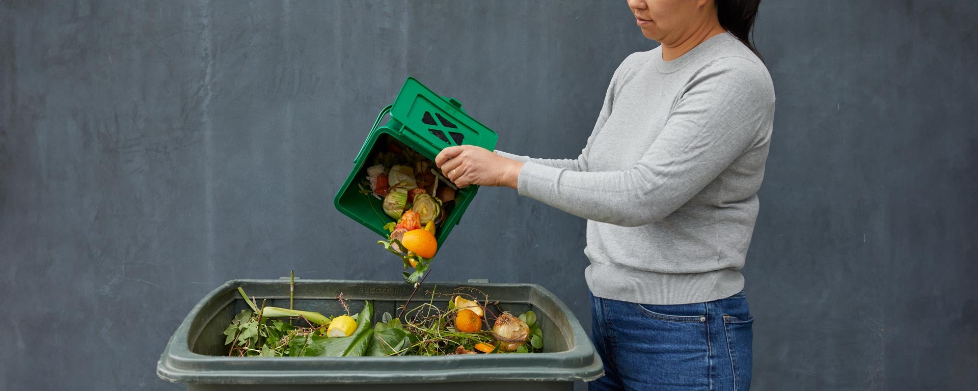 woman dumping food scraps into green waste bin