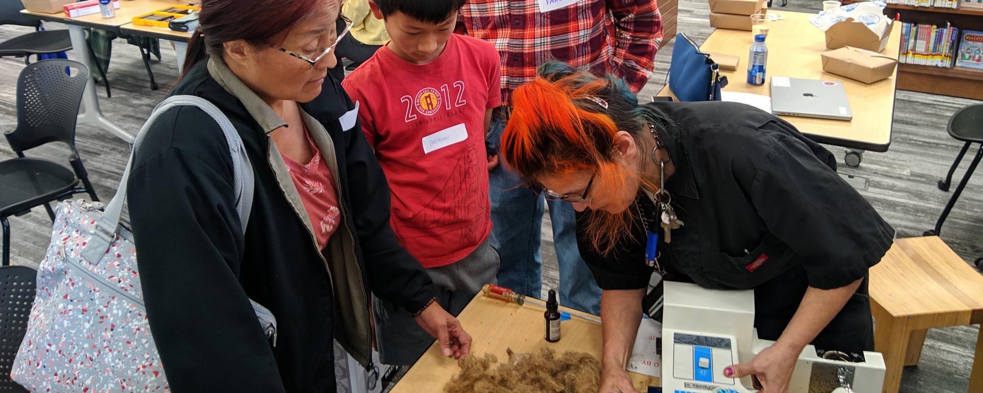 San Mateo County Fixit Clinic volunteer assists woman and grandson with sewing machine repair