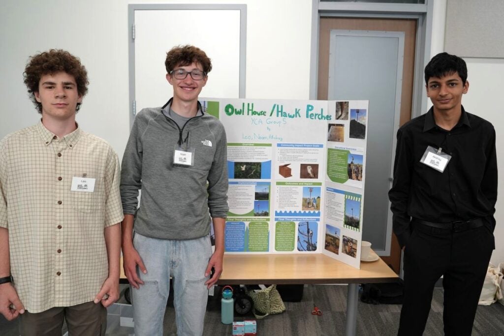 3 students posing in fron of their "Owl Habitat and Ecosystem Resilience" project poster