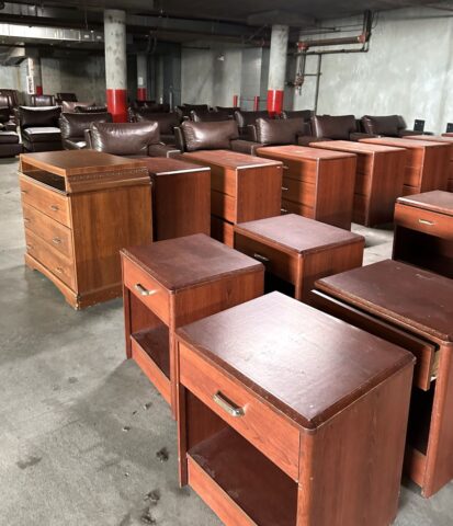 Image of a basement room with three rows of nightstands and dressers, with many rows of armchairs in the background.