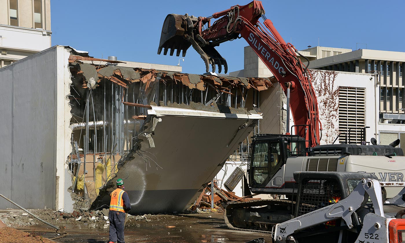 Construction crew demolishing building with tractor